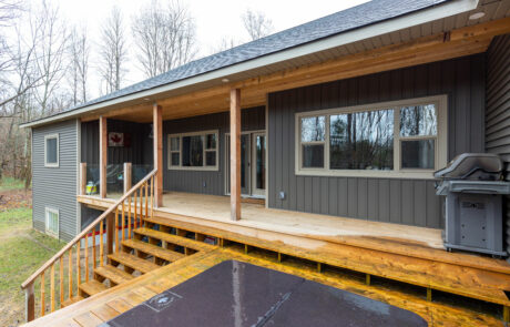 Muskoka Lakes backyard with full length porch & patio with hottub